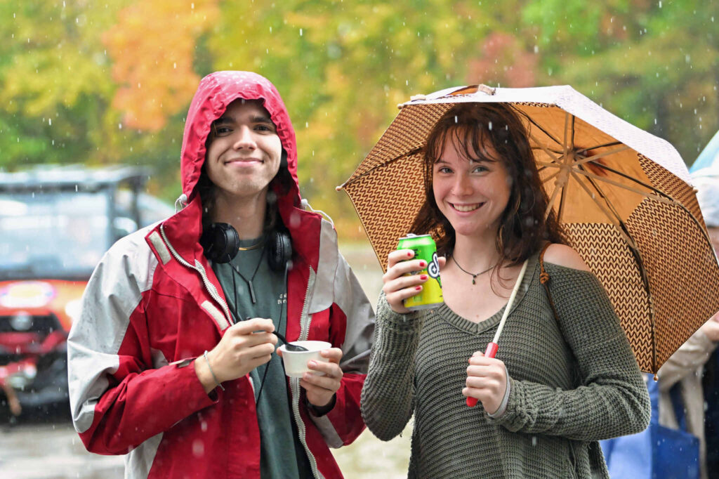 Students standing in rain with an umbrella