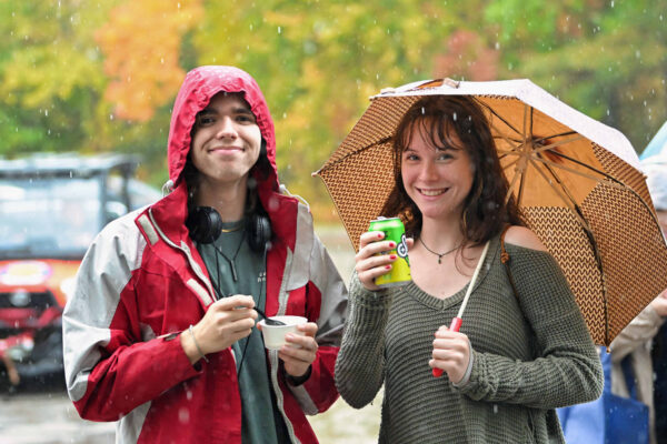 Students standing in rain with an umbrella