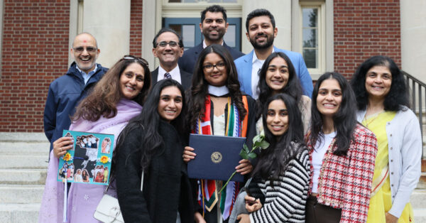 A graduate is proudly flanked by friends and family for a posed photo.