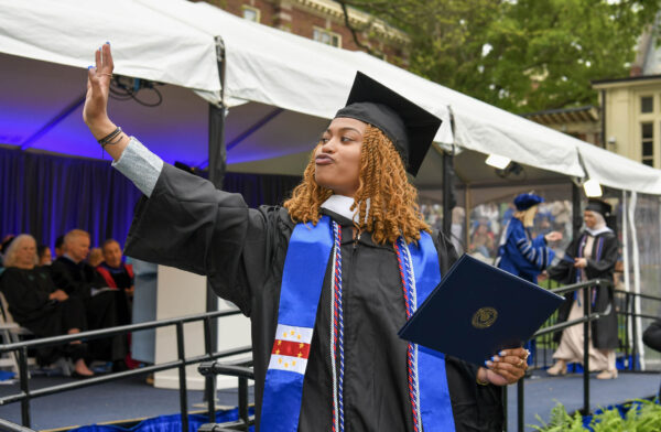 A graduate happily waves at the crowd after receiving their diploma.