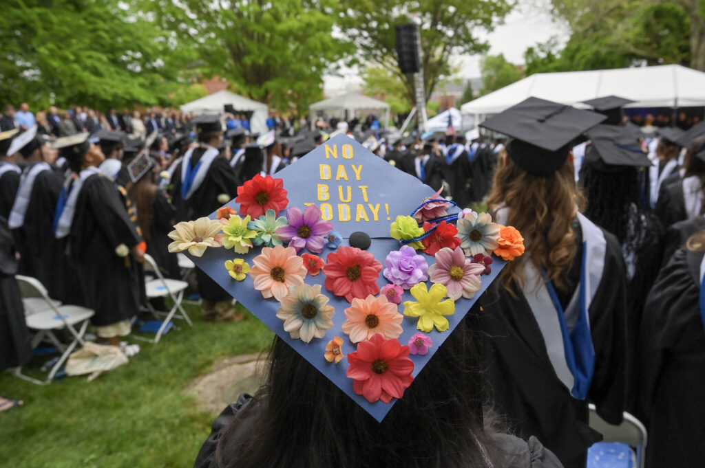 A beautifully decorated mortarboard with faux flowers reading: No day but today!